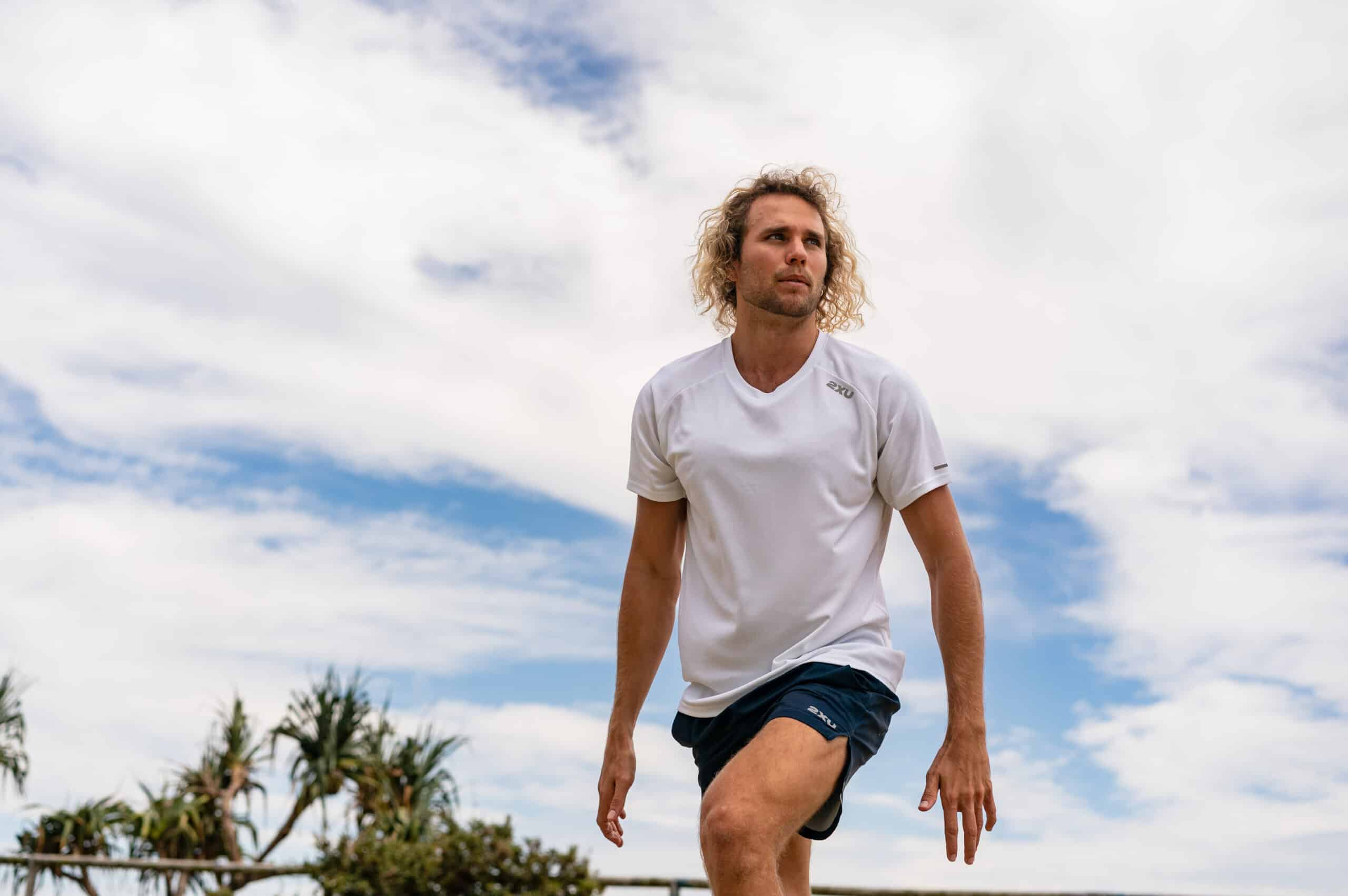 20-something white male in black athletic shorts and white t-shirt with a blue sky behind him