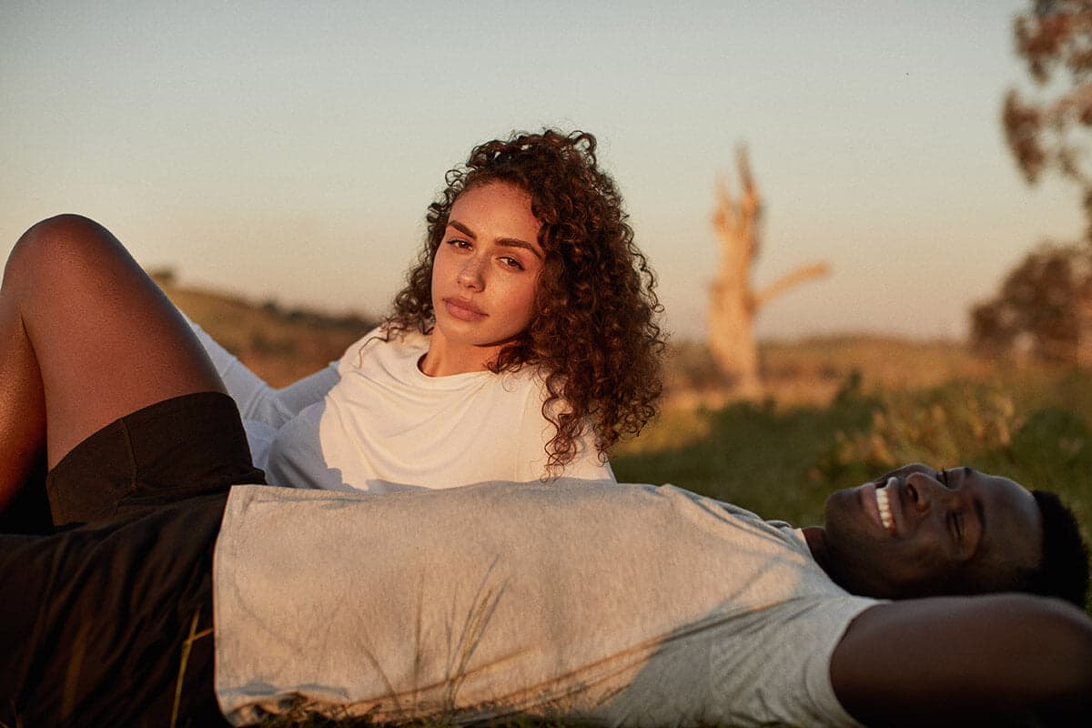 Young couple laying in field in casual wear