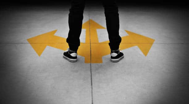 Young man feet and three yellow arrows painted on floor.