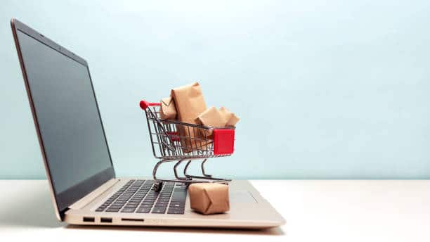 Shopping cart full of packages resting on top of a laptop 