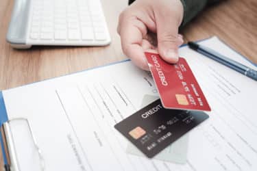 Close up hand a man hold credit cards on insurance document for payment of Annual car insurance expenses that must be paid regularly instead of using cash