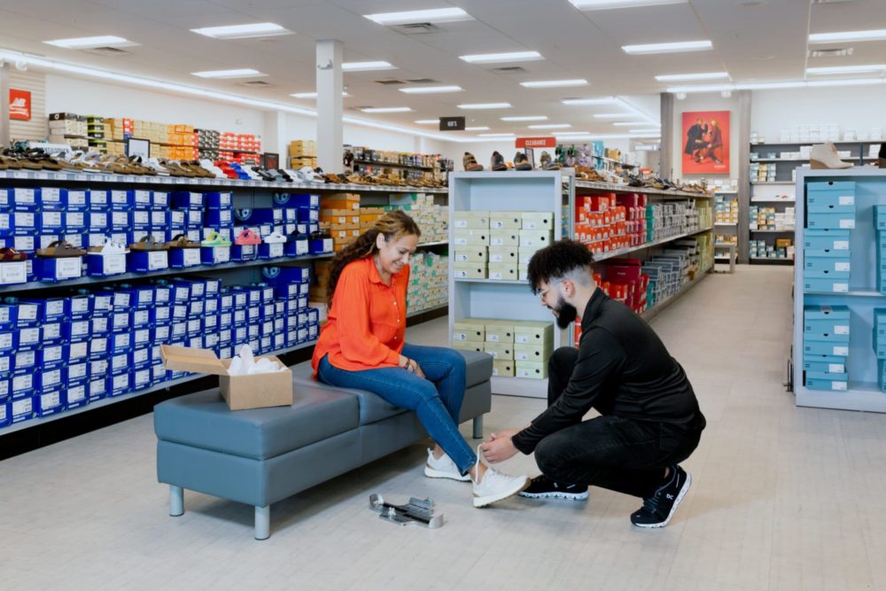 Males sales associate helping a woman try on shoes at Peltz Shoes