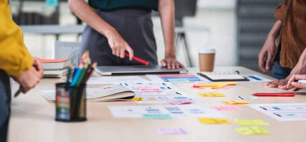 Close up ux developer and ui designer brainstorming about mobile app interface wireframe design on table with customer brief and color code at modern office.Creative digital development agency.panning