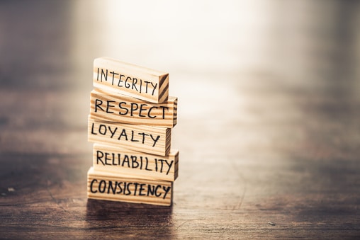 Businessman staking wood blocks with words hand written on them. He is explaining the integrity values.