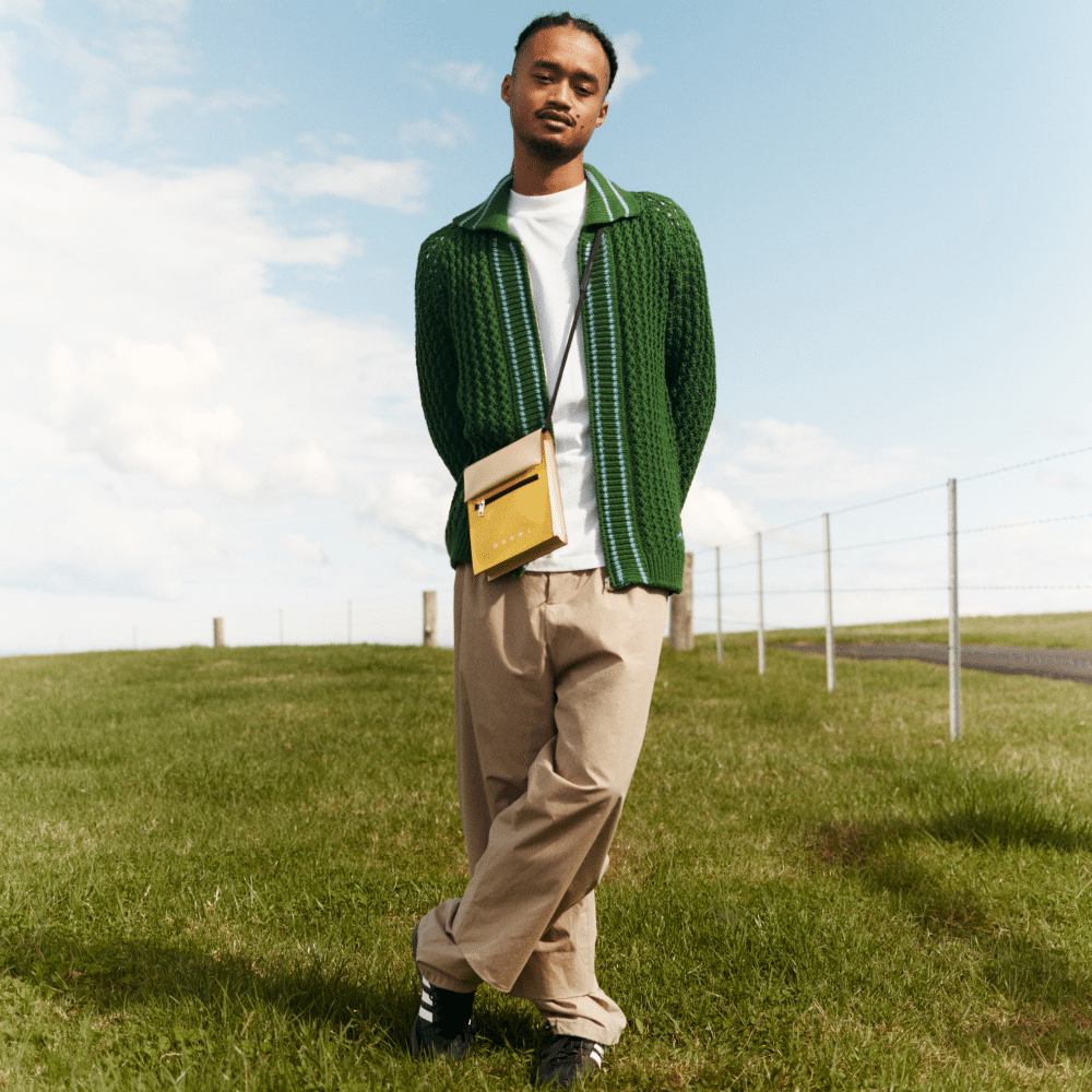 man in cardigan and tan pants in green field