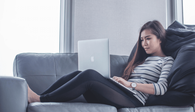 Woman sitting on couch with open MacBook