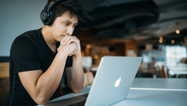 man wearing headphones sitting at macbook