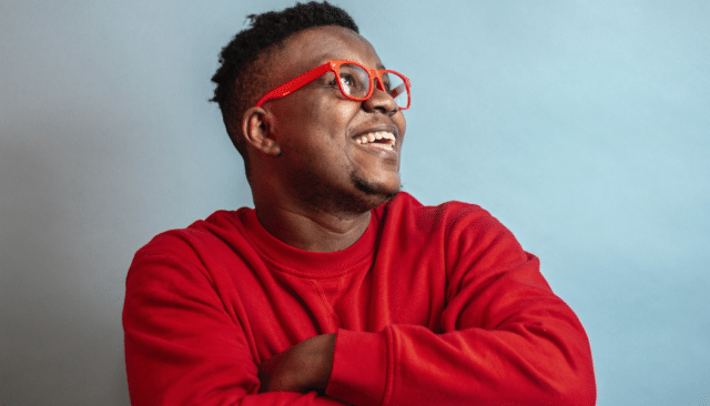 man in red shirt and red glasses with a big smile 